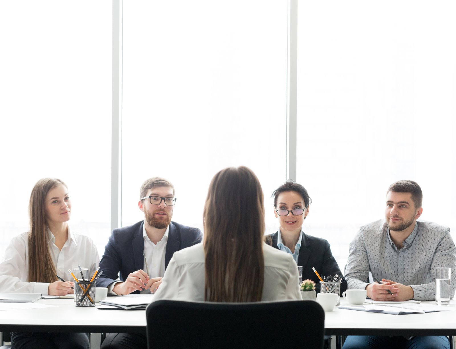Rekrutacja programistów – jakie pytania zadawać, aby wyłonić najlepszego kandydata? 7 hr managers having job interview with female candi 2023 11 27 05 04 31 utc